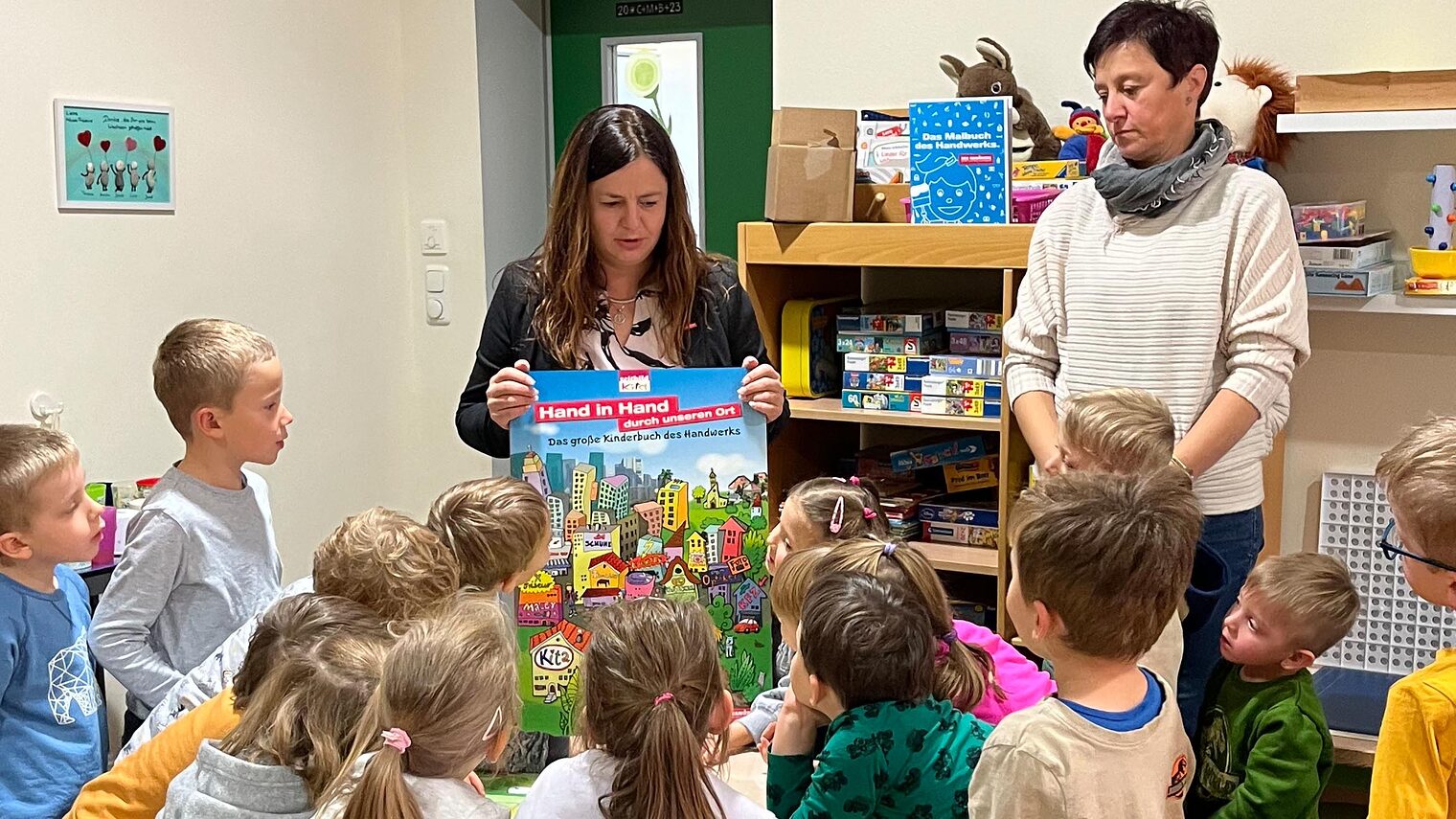 Kindergartenkinder stehen im Kreis und sehen sich das Wettbewerbsposter an. 