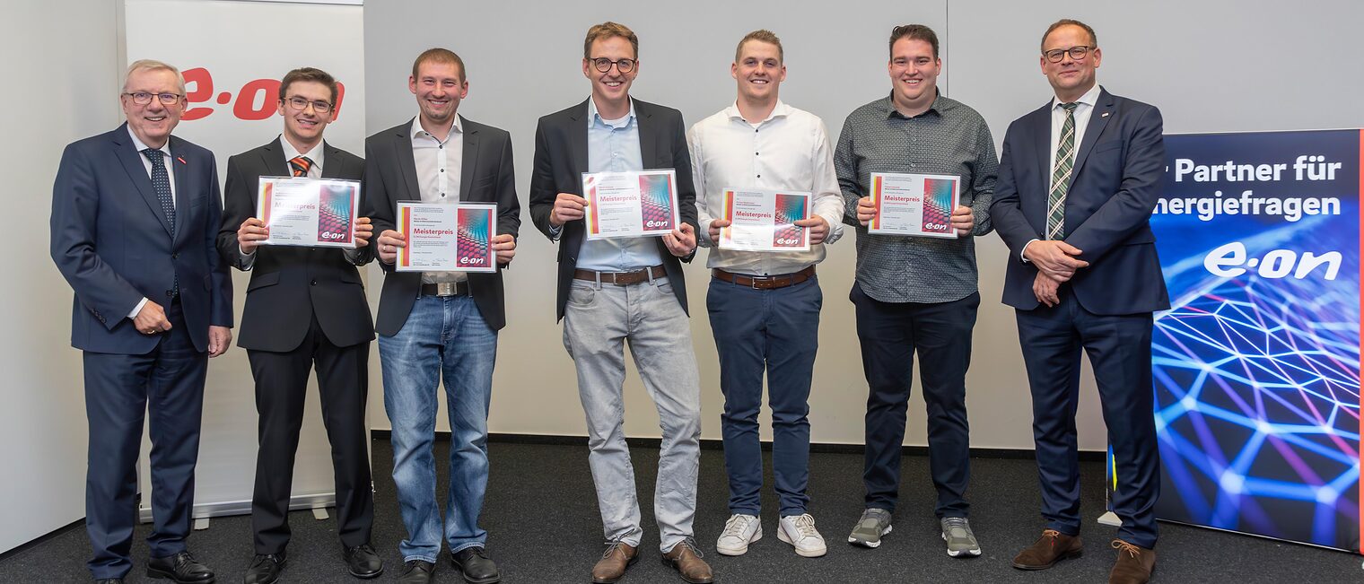 Verleihung Meisterpreis 2023 der Eon Energie Deutschland GmbH in Regensburg: (v.li.) HWK-Hauptgeschäftsführer Jürgen Kilger, Andreas Helmlechner, Martin Kißler, Martin Kettner, Florian Niedermeier, Fabian Lehmeier und Rolf Heiermann (Eon-Leiter Verkauf Energielösungen Region Süd). Die Gewinner stehen in einer Reihe und halten ihre Urkunden in den Händen.