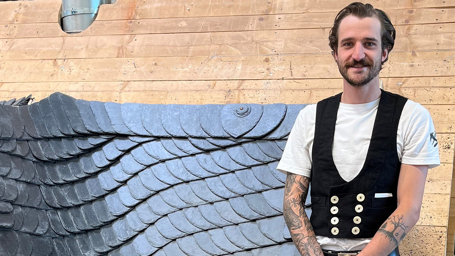 Der Meisterbeste Philipp Hackl steht vor seinem Meisterstück: Eine rechte Hauptkehle aus Schiefer. 