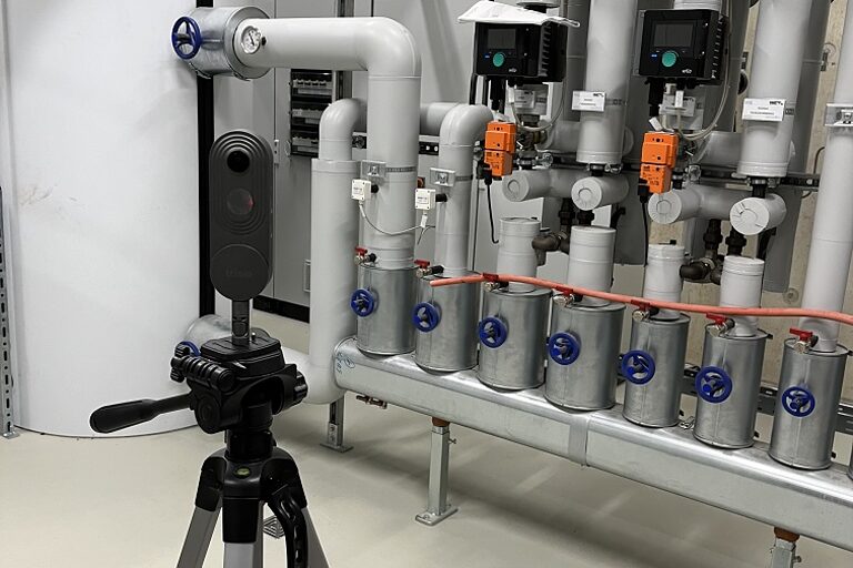 Aufgebaute 360-Grad-Kamera in einer Halle vor Rohrleitungen.