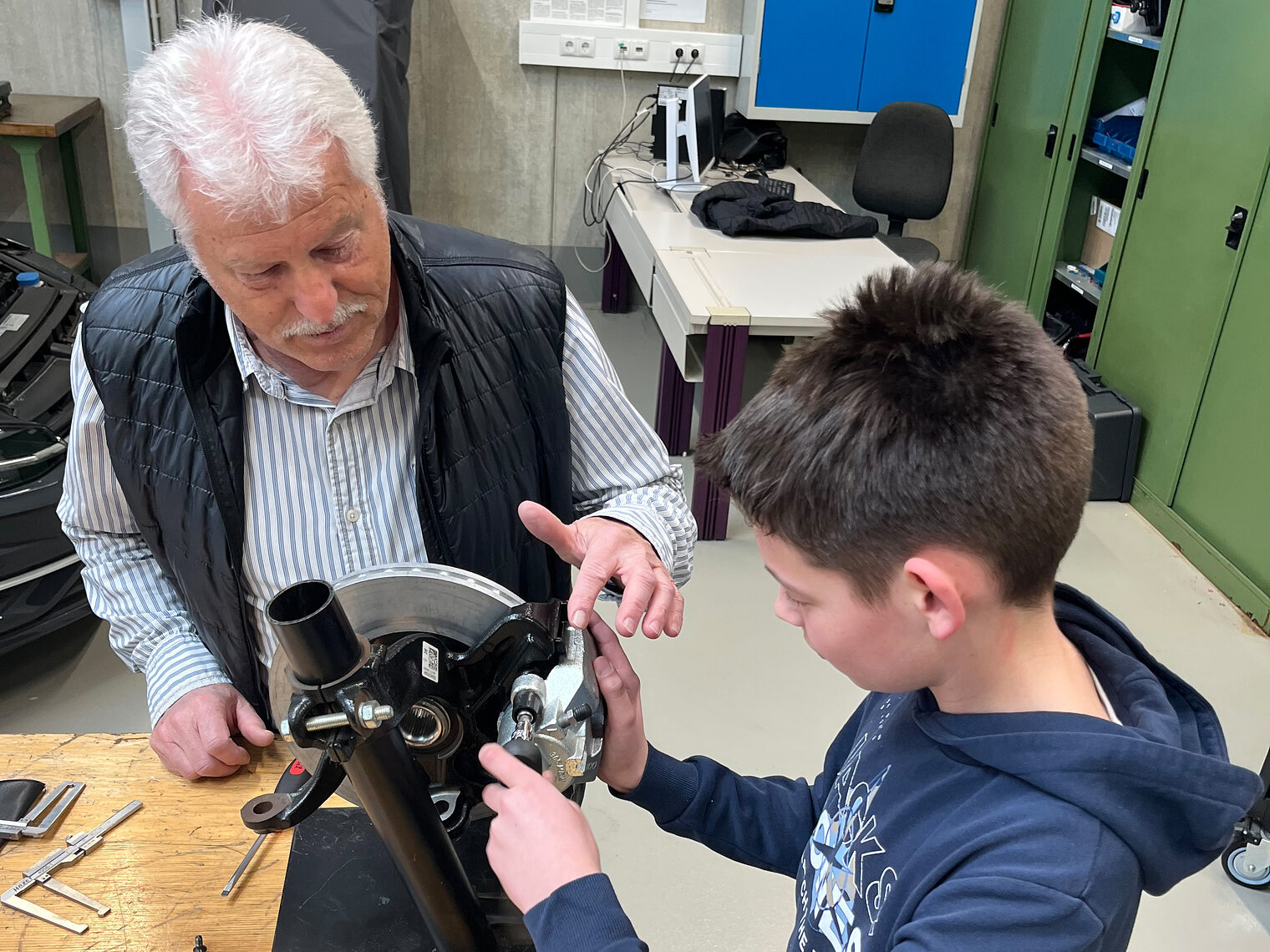 Ein Schüler wechselt gemeinsam mit dem Ausbilder Karl-Heinz Knaus Bremsklötze.