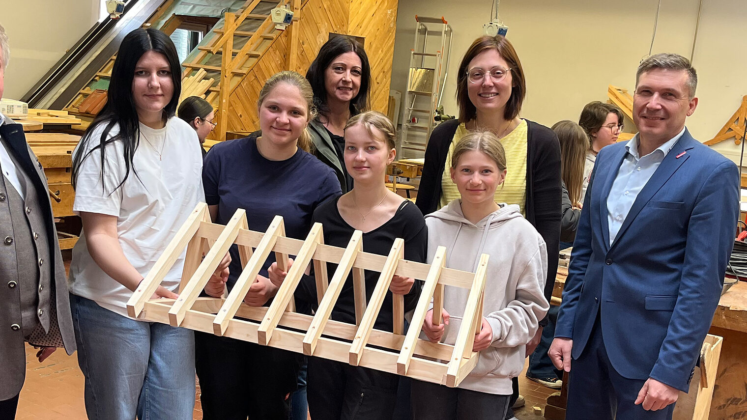Schülerinnen der Sophie-Scholl-Realschule halten einen selbstgezimmerten, kleinen Dachstuhl in die Kamera. 