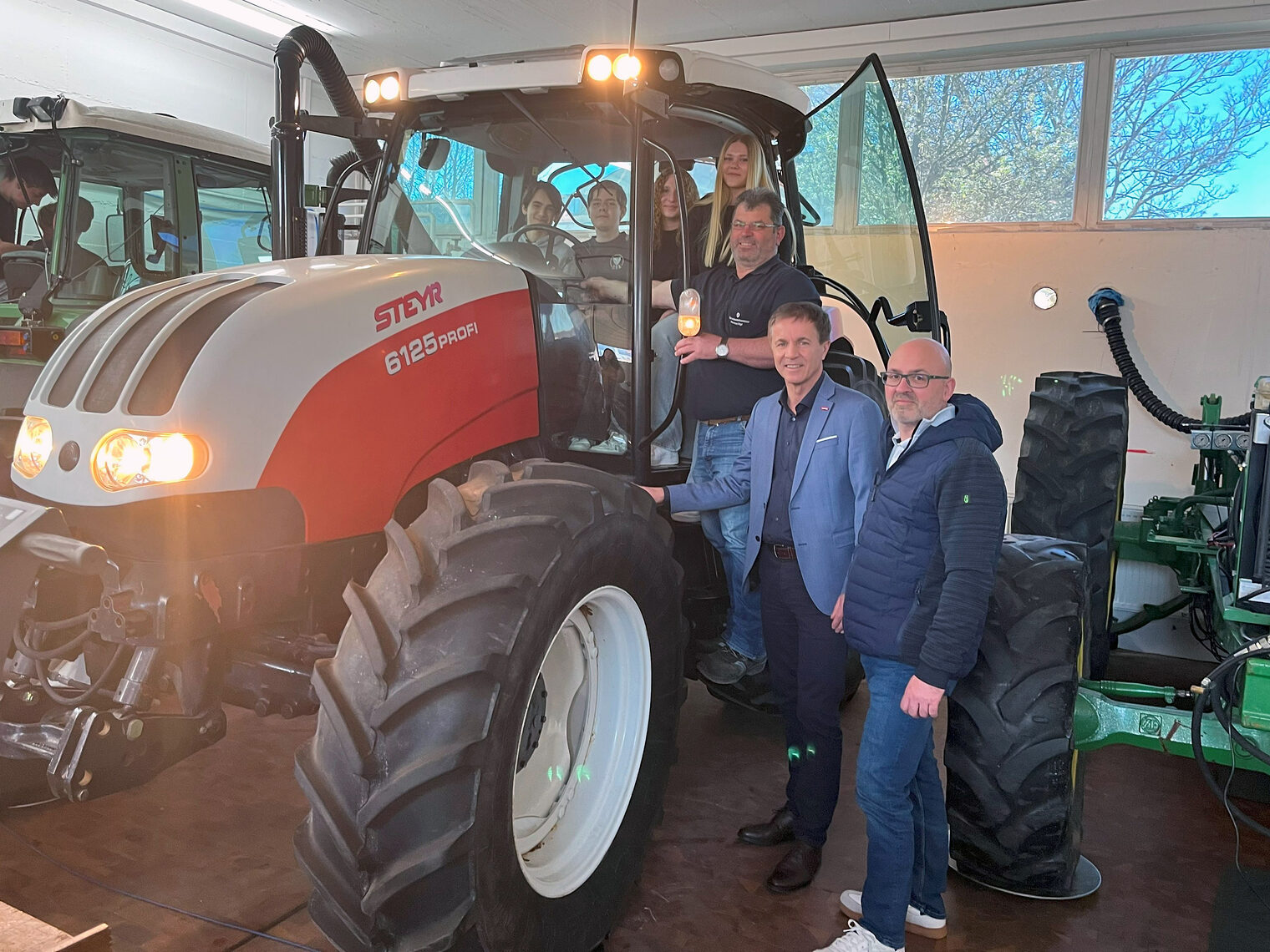 Schüler und Ehrengäste posieren im großen Traktor von Steyr für das Bild.