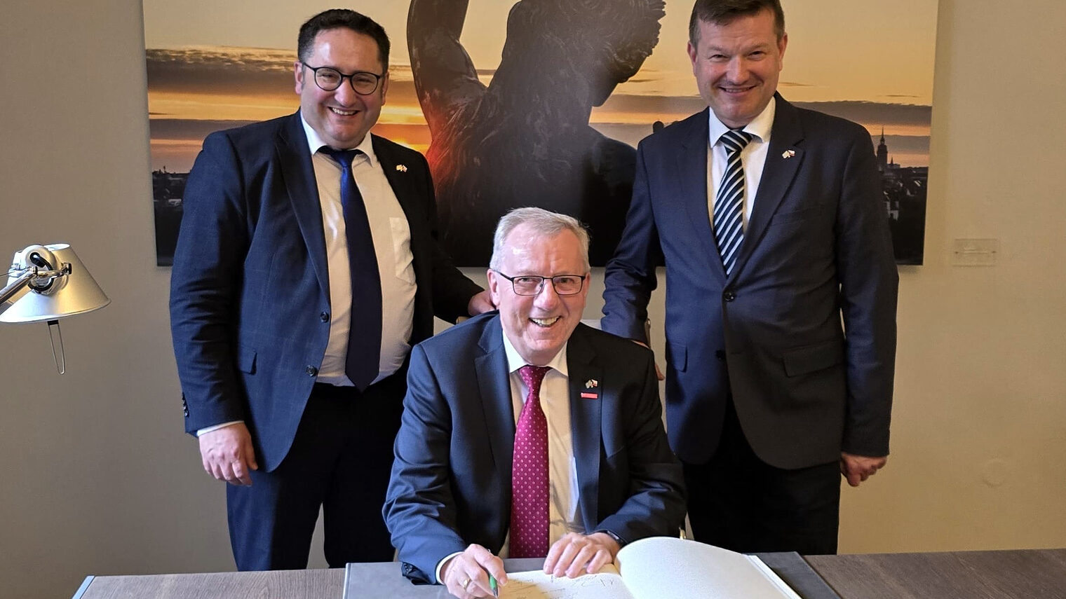 Hauptgeschäftsführer Jürgen Kilger trägt sich ins Gästebuch der bayerischen Repräsentanz in Prag ein. Staatssekretär Tobias Gotthardt (li.) und dem Leiter der Repräsentanz Martin Kastler stehen mit dabei.