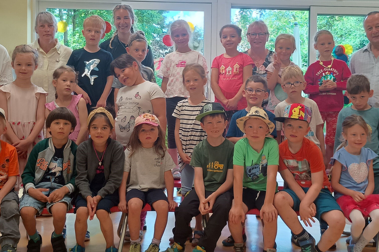 HWK-Vizepräsident Christian Läpple (rechts) zu Besuch beim Kindergarten „Bergzwergerl“. Die Kindergartengruppe, Erwachsene und HWK-Vizepräsident Christian Läpple stehen und sitzen in einem Raum mit großen Fenstern.