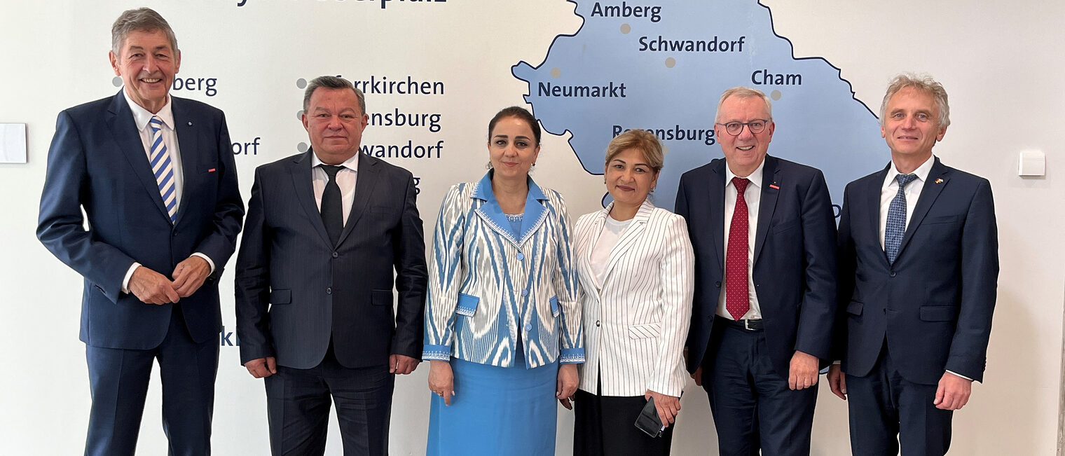 Die Handwerkskammer Niederbayern-Oberpfalz empfing tadschikische Gäste. Sechs Personen, darunter Vertreter der Handwerkskammer, stehen in formeller Kleidung vor einer Karte der Region Niederbayern-Oberpfalz.