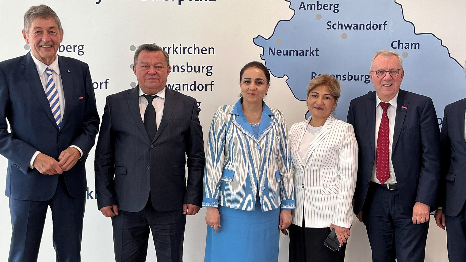 Sechs Personen, darunter Vertreter der Handwerkskammer, stehen in formeller Kleidung vor einer Karte der Region Niederbayern-Oberpfalz.