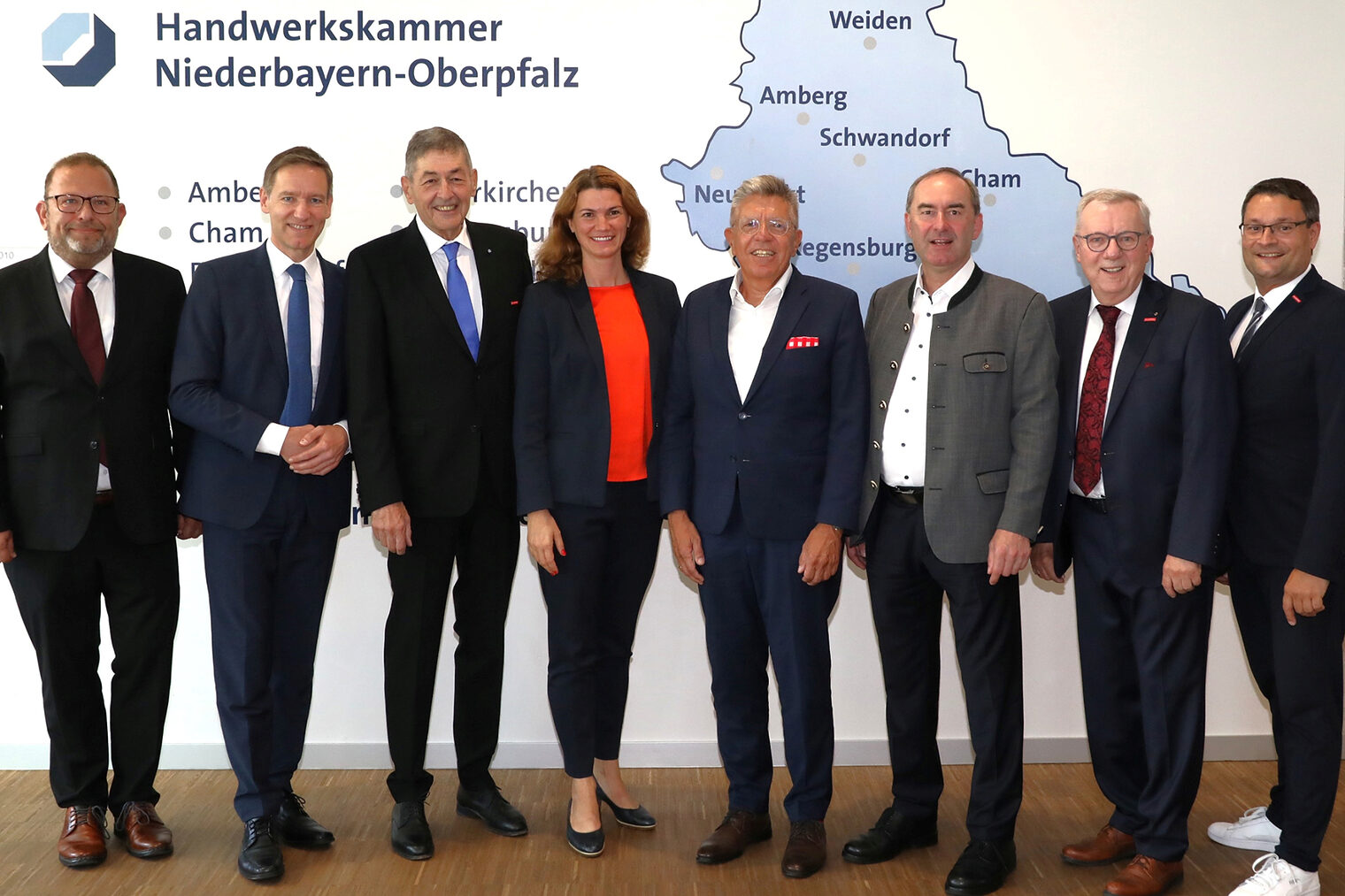 Die Ehrengäste der Festveranstaltung sehen die Handwerkskammer Niederbayern-Oberpfalz für zukünftige Aufgaben gut aufgestellt. Die Ehrengäste der Festveranstaltung stellen sich vor der Wand mit der Karte von Niederbayern und Oberpfalz für das Foto auf.