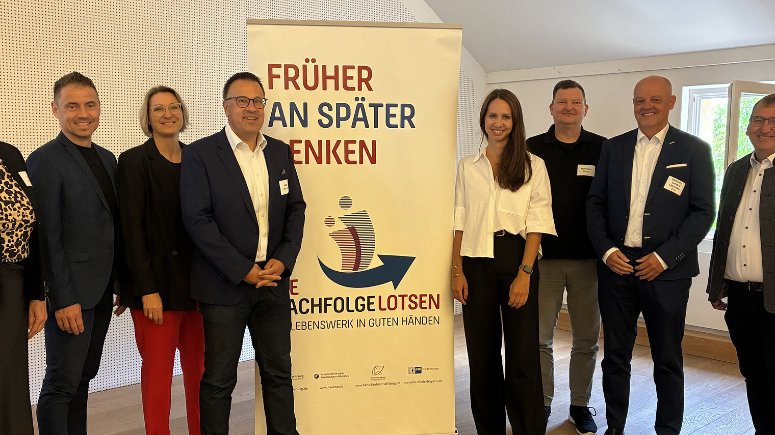 Die Organisatoren der Nachfolgelotsen freuen sich über eine gelungene Veranstaltung. Sie stehen vor dem Banner "Früher an später denken."