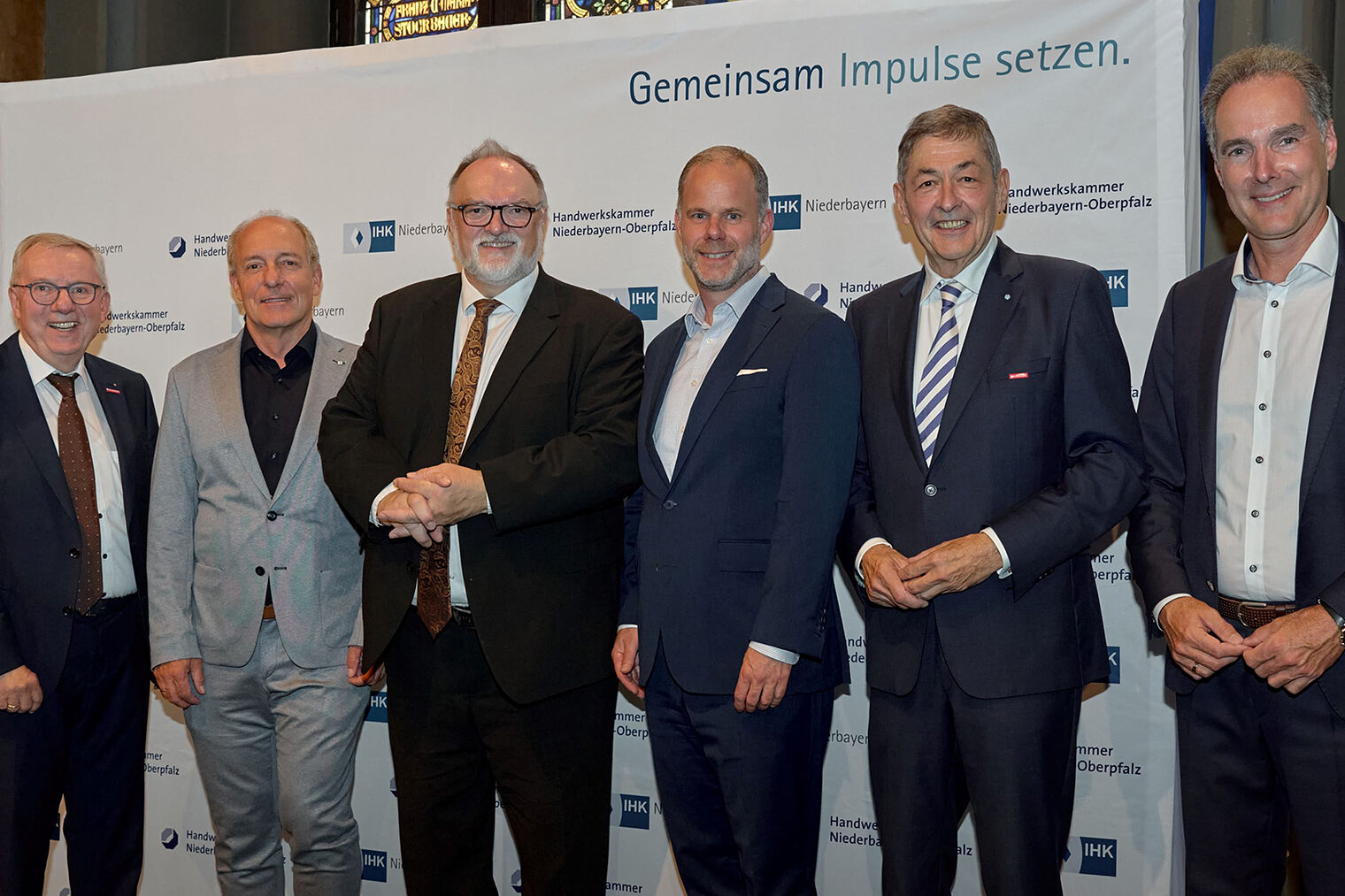 Die Vertreter von IHK und Handwerkskammern regten zum gemeinsamen Handeln und offener Kommunikation an, um die Region wettbewerbsfähig zu halten. Die Vertreter von IHK und Handwerkskammern stehen vor der Pressewand der IHK Niederbayern und platzieren sich für ein Foto.