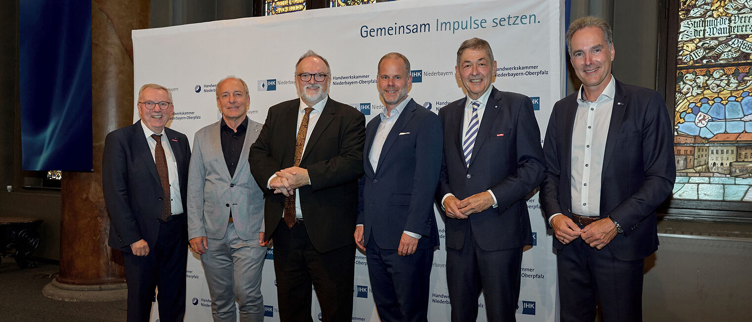 Die Vertreter von IHK und Handwerkskammern stehen vor der Pressewand der IHK Niederbayern und platzieren sich für ein Foto. 