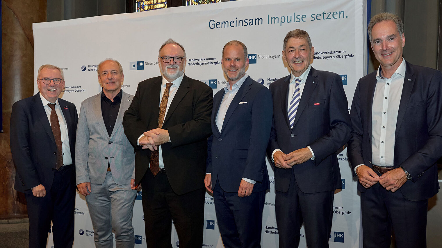 Die Vertreter von IHK und Handwerkskammern stehen vor der Pressewand der IHK Niederbayern und platzieren sich für ein Foto. 