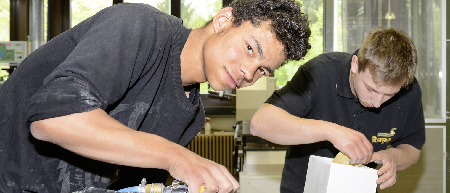 Ein junger Mann benutzt ein Schleifgerät.