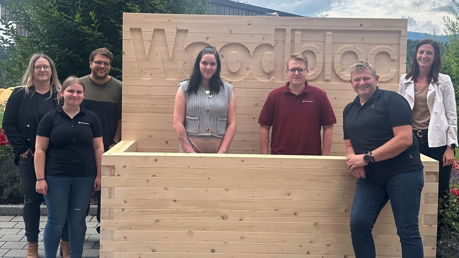 Die Auszubildenden der Firma Penzkofer Bau GmbH haben ein komplett aus Holz gefertigtes Hochbeet gebaut. Für das Foto posieren sie darin.