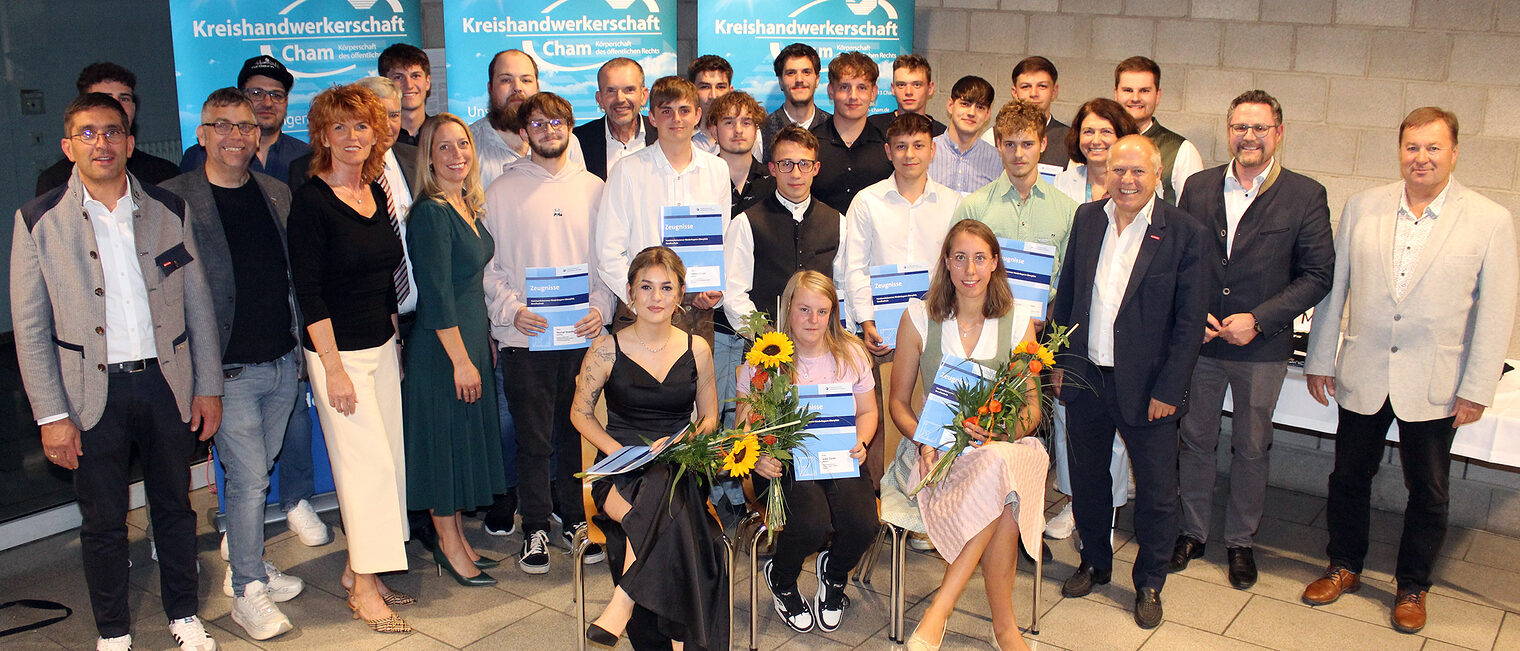 Sie freuen sich gemeinsam mit den Ehrengästen über ihren Gesellenbrief. Die Damen halten Blumen in den Händen.