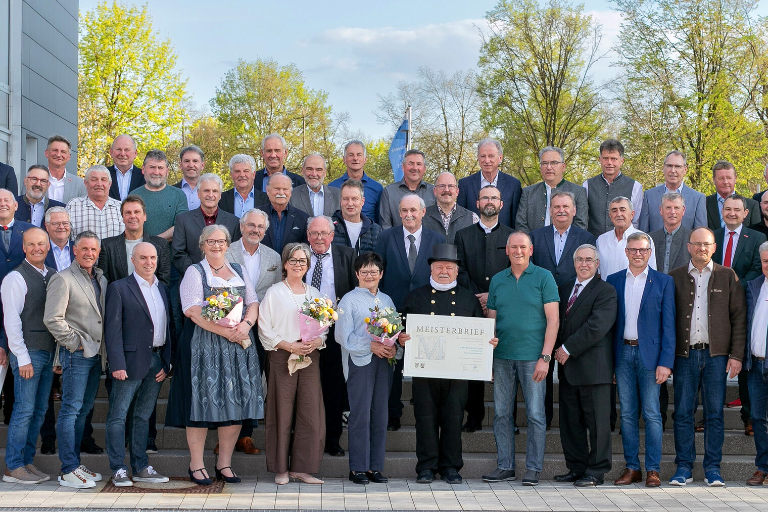 46 Handwerksmeisterinnen und Handwerksmeister mit HWK-Vertretern vor der Handwerkskammer bei der Verleihung der Goldenen Meisterbriefe.