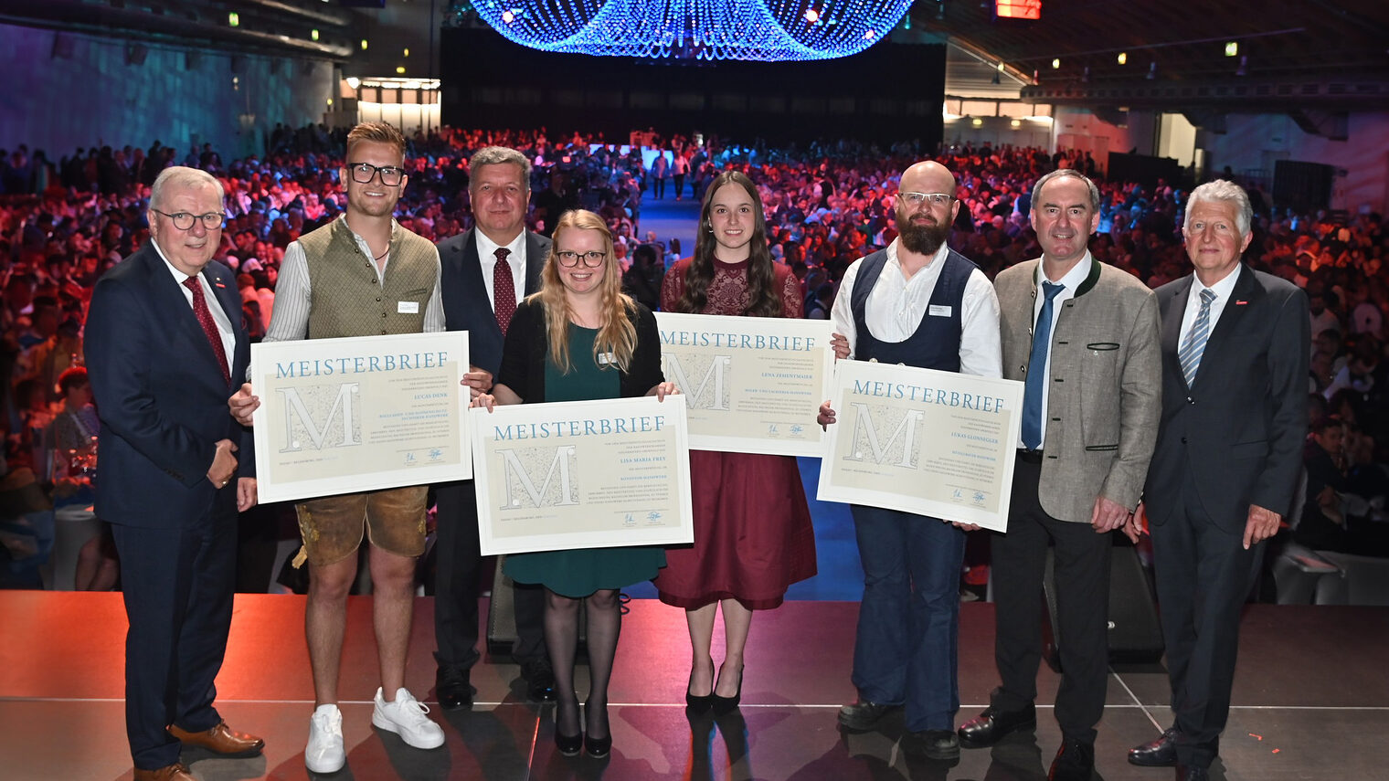 Vier Meister erhalten auf der Bühne ihre Meisterbriefe von Staatsminister Hubert Aiwanger und Hauptgeschäftsführer Jürgen Kilger.