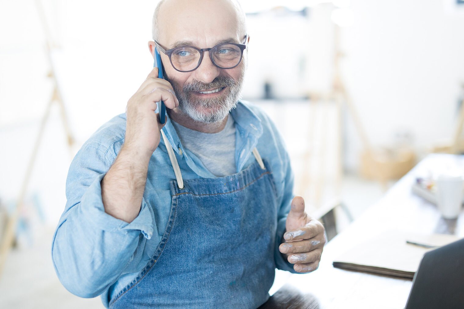 Ein Handwerker telefoniert im Büro und erledigt Arbeiten am Laptop.